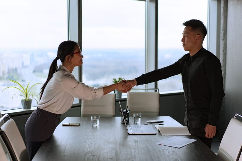 Two professionals shaking hands in a corporate office