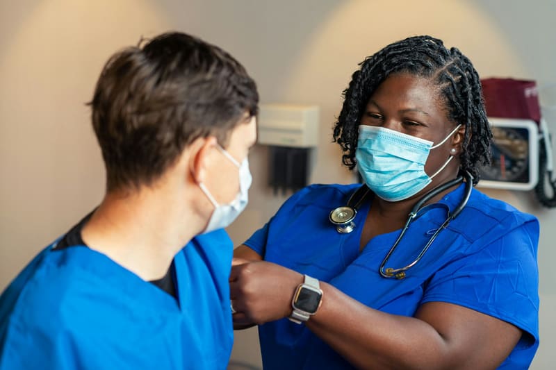 A nurse reviewing a chart with a colleague on a hospital ward